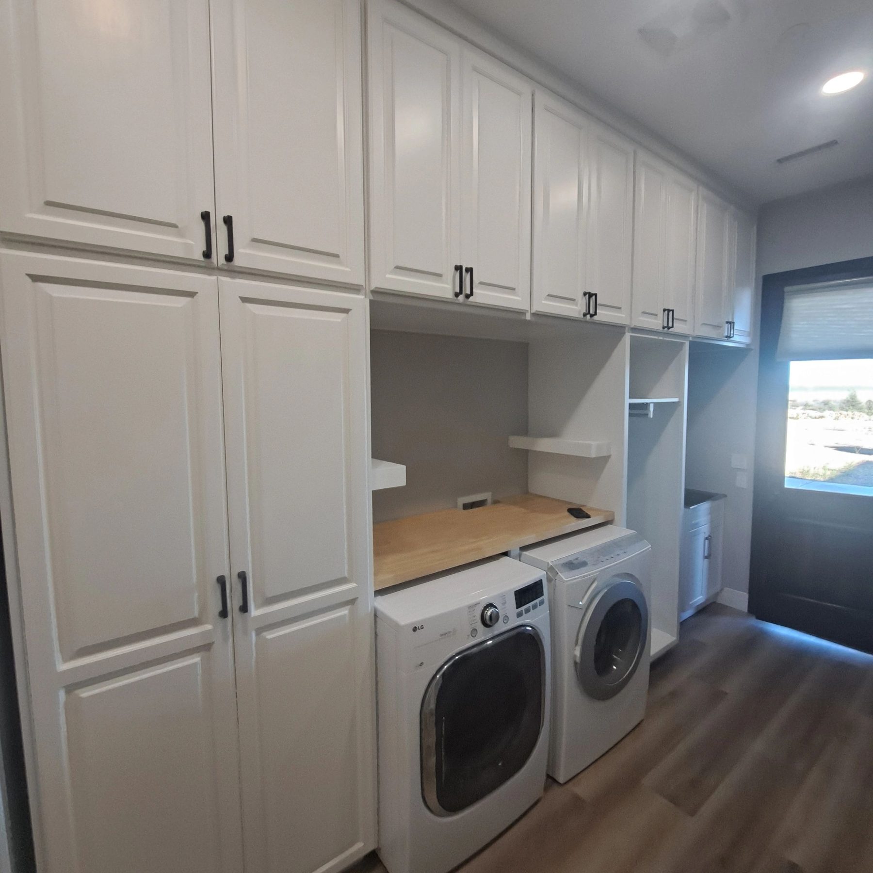 White custom laundry room cabinetry built around a washer and dryer