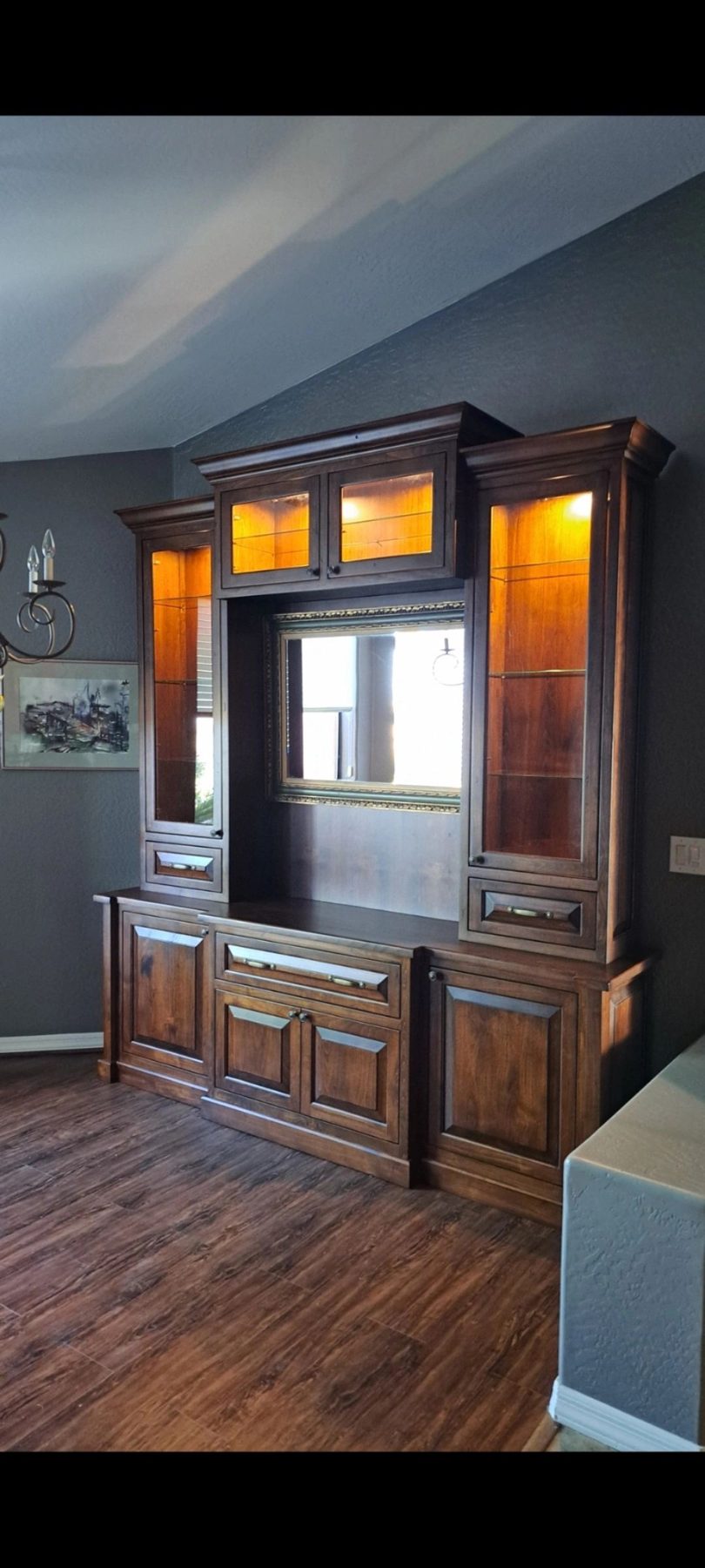 Dark stained wood custom entertainment center with lit glass display cabinets